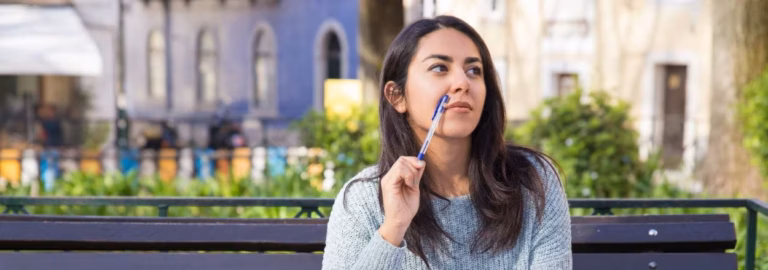 Joven sentada en un banco al aire libre mientras aprovecha para repasar sus apuntes al estudiar inglés en Irlanda.