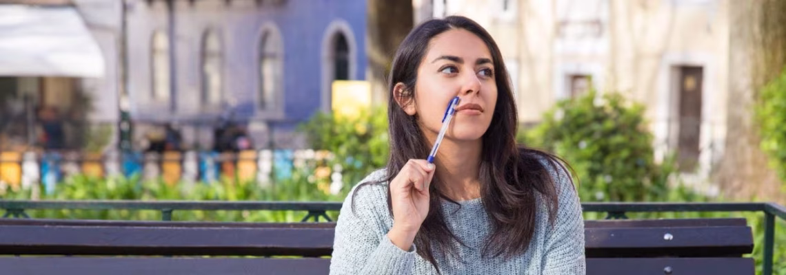 Joven sentada en un banco al aire libre mientras aprovecha para repasar sus apuntes al estudiar inglés en Irlanda.